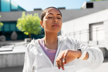 young black woman with smart watch breathing outdoors to illustrate 4-7-8 breathing for weight loss