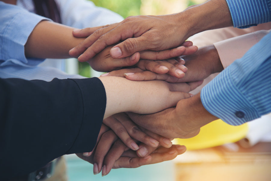 Many hands, one on top of the other, to illustrate support groups after weight loss surgery and the importance of Postoperative Support.