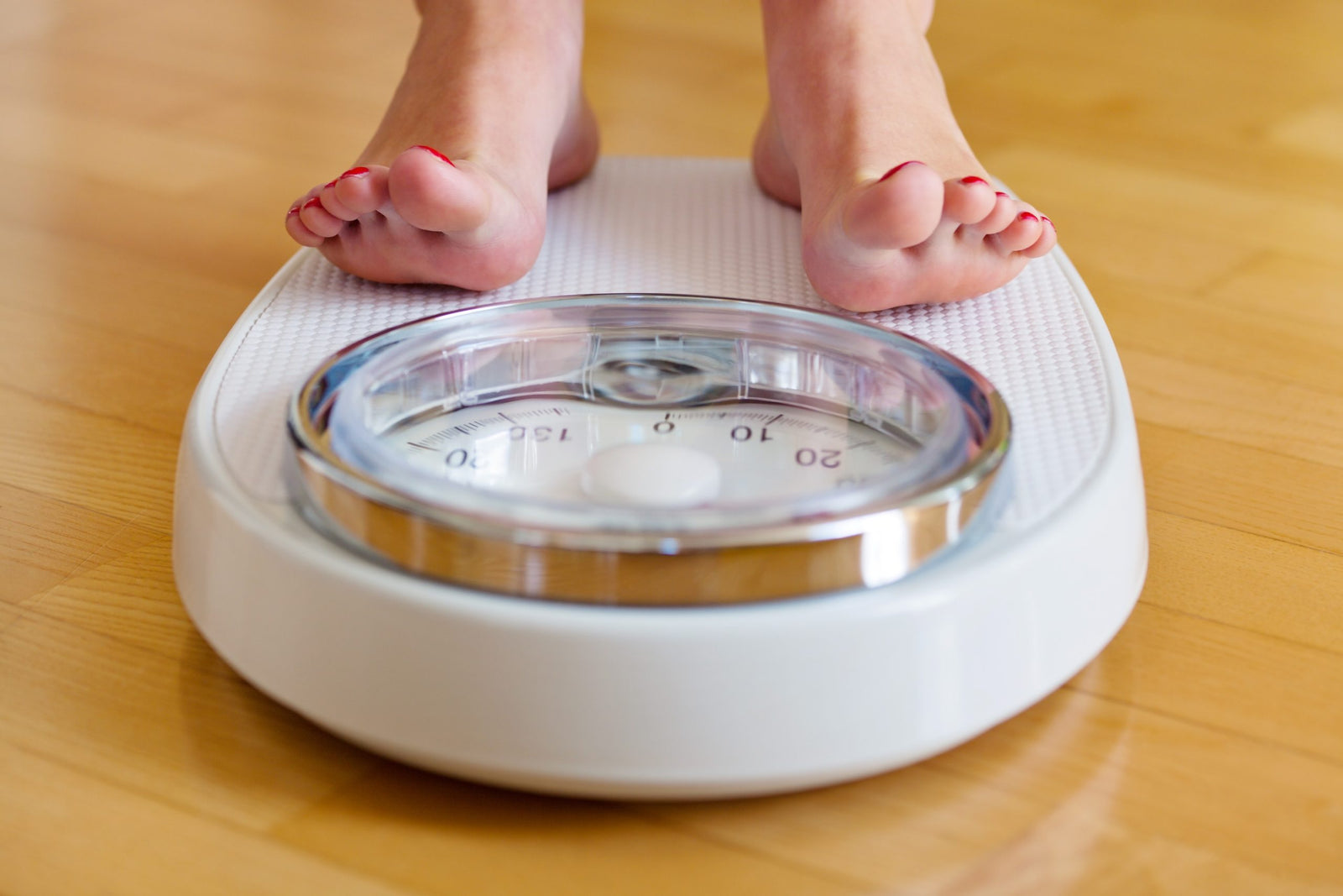 young woman's feet on a bathroom scale to illustrate Can My Teenager Get Bariatric Surgery