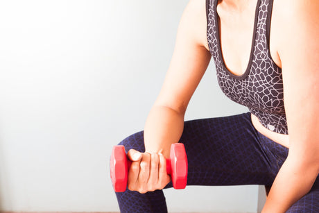 Woman holding red dumbbells to illustrate How Do You Get Rid Of Loose Skin After Weight Loss Surgery