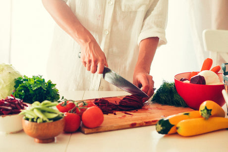 Woman is cooking at the kitchen ( slicing vegetables ) to illustrate How To Restart Weight Loss After Gastric Bypass