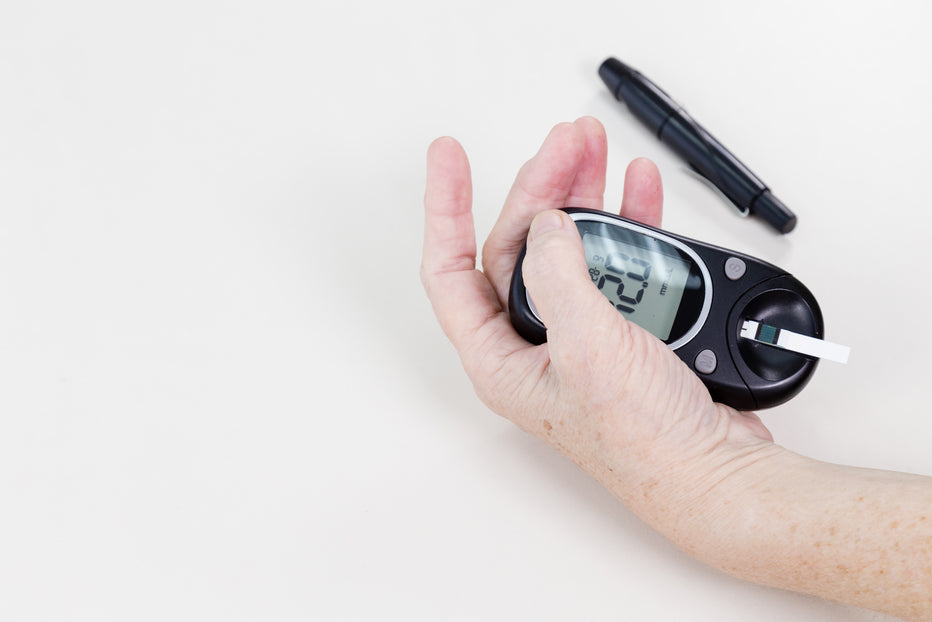 Elderly hands holding blood sugar level machine for diabetes.