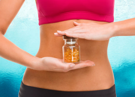 A slender woman with a bare midriff holding a bottle of pills to help illustrate Based on BMI When is Surgery Better Than Weight Loss Pills?