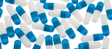 A lot of blue and white pills on an illuminated table to illustrate Do Drugs That Make You Lose Weight Actually Work?