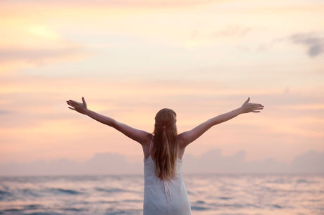 Woman with arms up at the beach to illustrate how much weight can I lose and Improved Quality of Life After Weight Loss Surgery