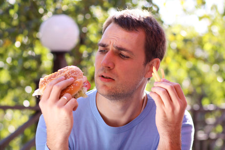 Young man eating burger at fast food restaurant to show obesity and fast food in america