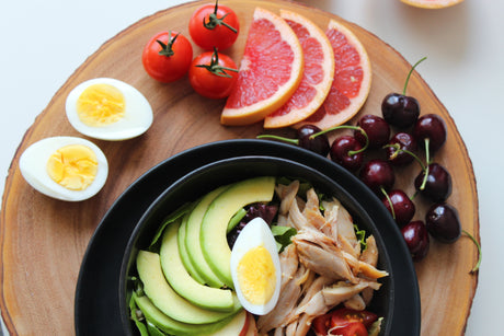 A plate of hard boiled eggs, grapefruit, cherries, avocado, and chicken to illustrate Diet after weight loss surgery and postoperative dietary guidelines.