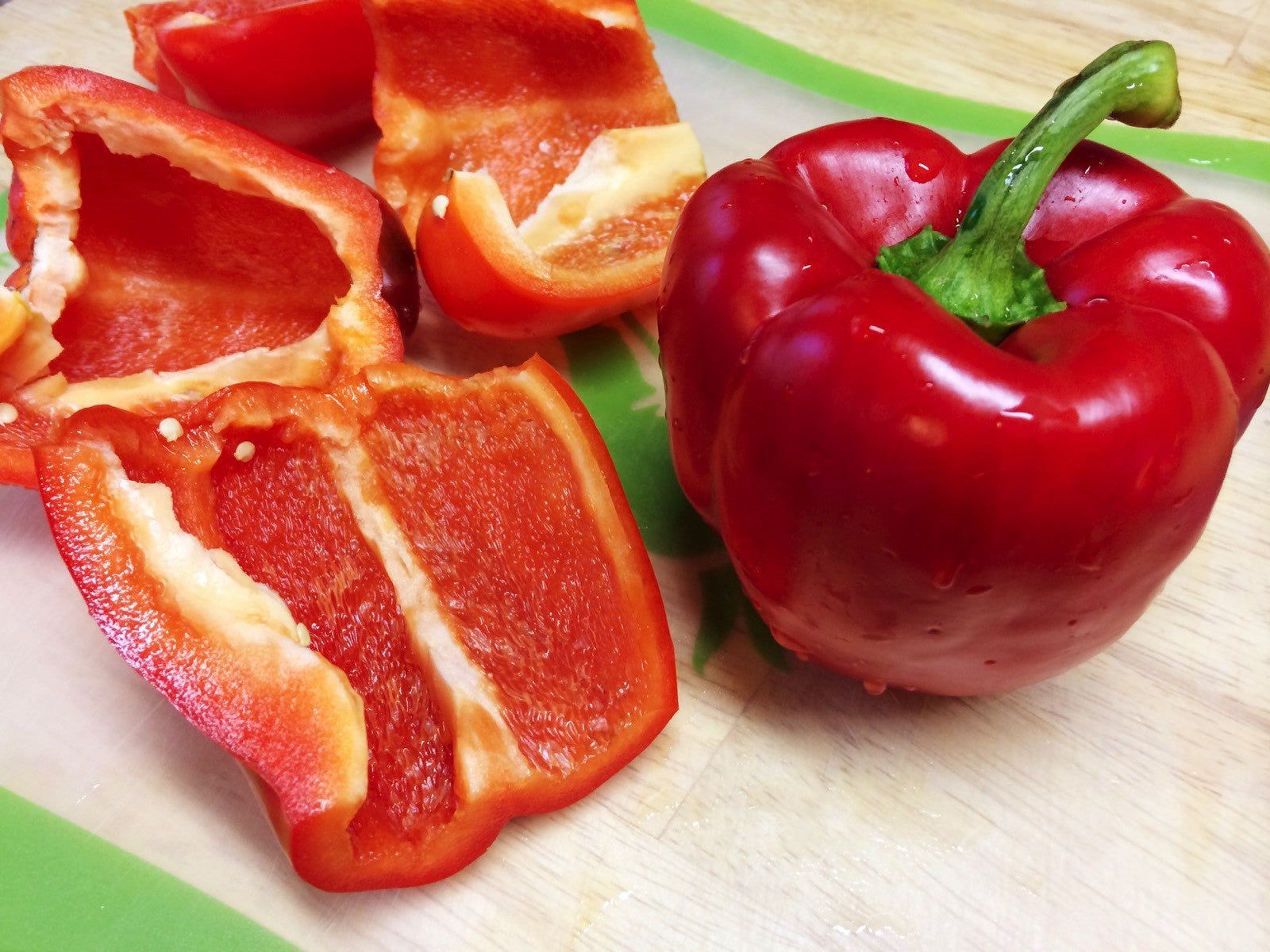 A whole red pepper and several sliced red pepper