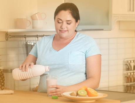 A woman pouring a liquid into a glass in her kitchen to help illustrate can I eat the night before gastric sleeve surgery and Bariatric Surgery vs. Dieting
