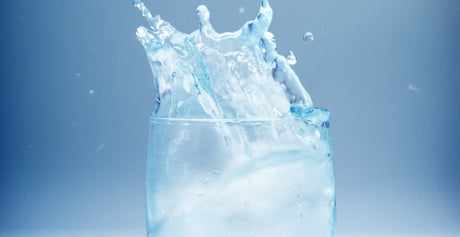 Water splashing out of a glass to illustrate too much water after gastric sleeve and Hydration and Fluid Intake After Bariatric Surgery