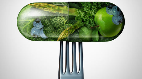 A pill or medicine capsule with fresh fruit and vegetables inside on a fork.