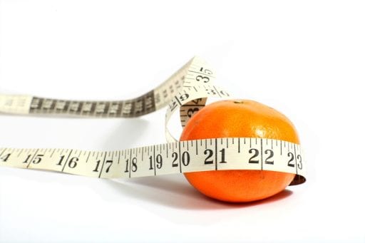 Photo of an orange with measuring tape around it, symbolizing dieting.