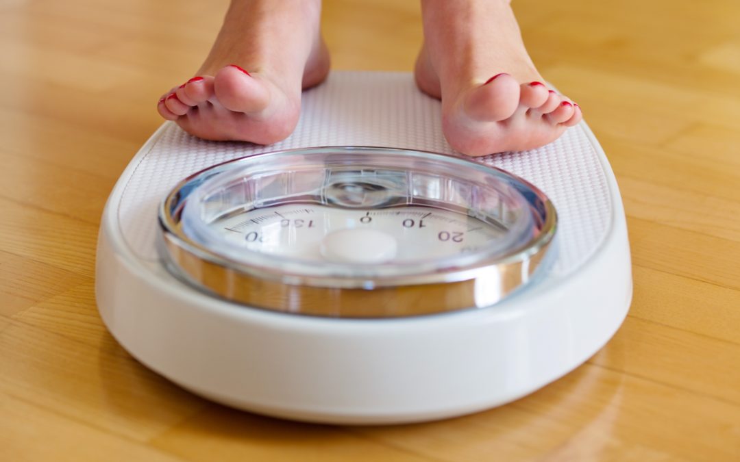 young woman's feet on a bathroom scale to illustrate Can My Teenager Get Bariatric Surgery