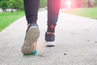 Photo of a person walking with sports shoes on a park pathway
