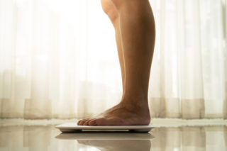 young woman standing on digital weight scale to illustrate Mini Gastric Bypass Oklahoma City Why We Don’t Recommend It