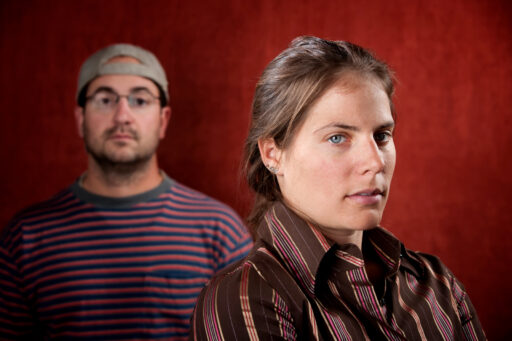 An upset woman looking at the camera with an expressionless man in the background to illustrate Navigating Relationship Challenges After Bariatric Surgery