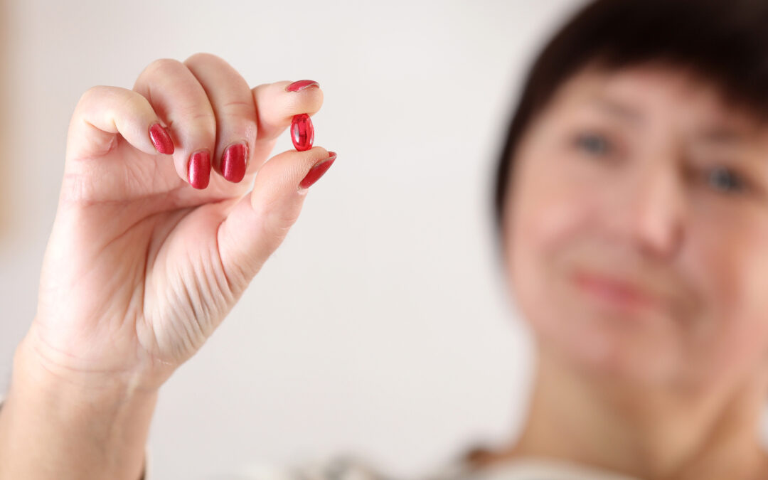 A smiling woman slightly burred holding a red pill in focus to help illustrate bariatric probiotics