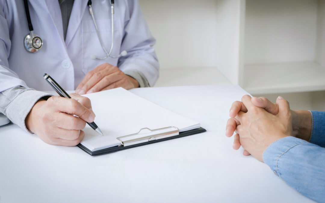 A doctor writing on a clipboard while talking to a patient to illustrate checklist for bariatric surgery