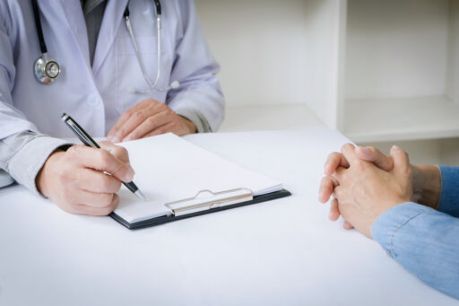 A doctor writing on a clipboard while talking to a patient to illustrate checklist for bariatric surgery