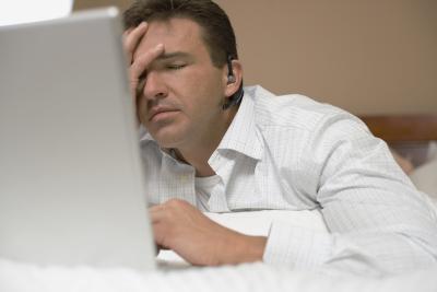 Man in front of computer rubs forehead because he is in pain to illustrate How Long Does Dumping Syndrome Last?
