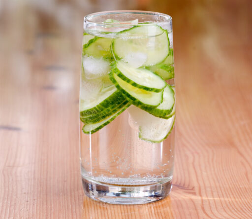 A glass of water with cucumbers in it.