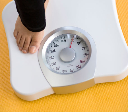Closeup of a scale as someone steps onto it to help illustrate how to prepare for bariatric surgery.