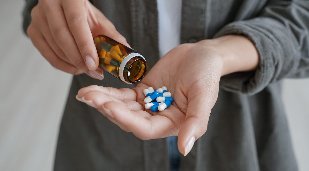 A woman pouring pills into her hand from a bottle to illustrate limitations of weight loss drugs.