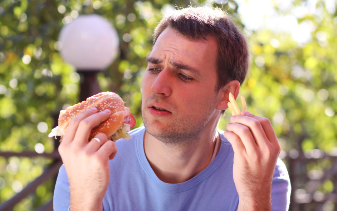 Young man eating burger at fast food restaurant to show obesity and fast food in america