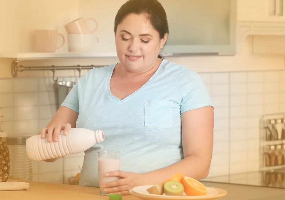 A woman pouring a liquid into a glass in her kitchen to help illustrate can I eat the night before gastric sleeve surgery?