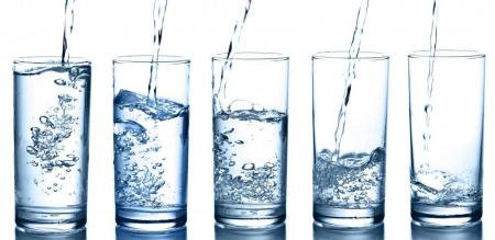 An image of five glasses being filled with water to help illustrate the 10 signs of dehydration after surgery.