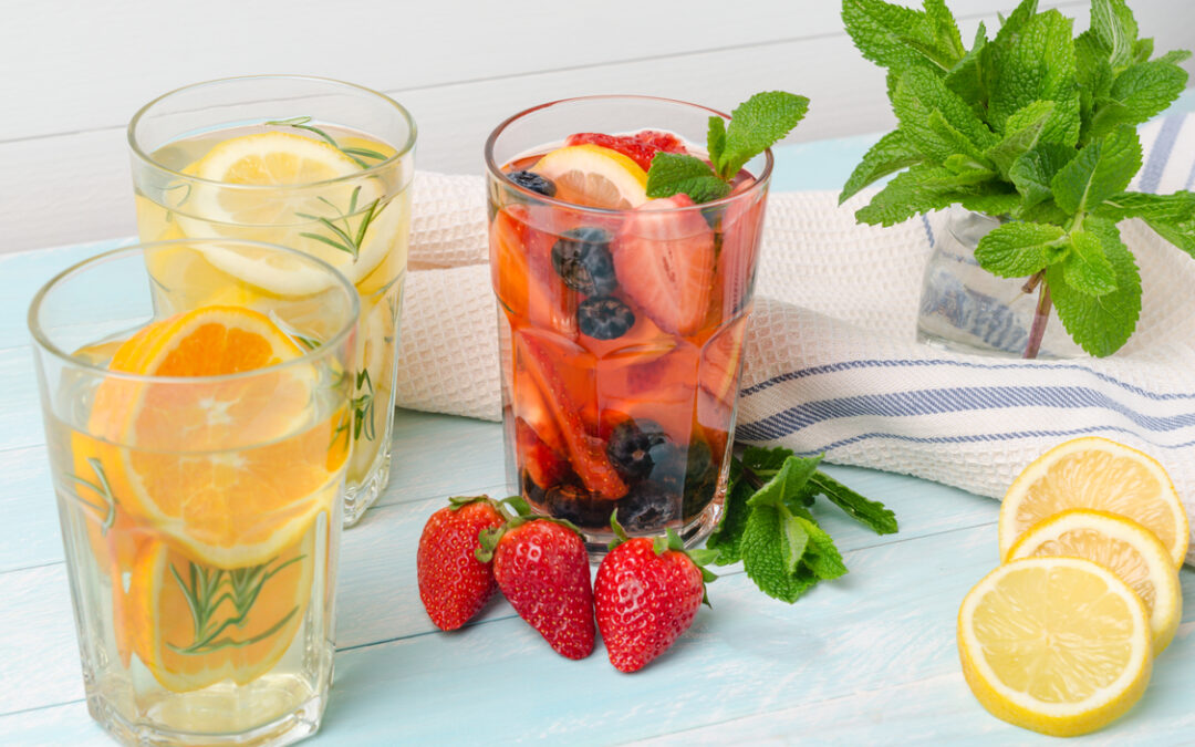 Three examples of fruit-infused water (orange, lemon, and a mixture of strawberry, blueberries, and lemon) to illustrate ways to make water taste better.