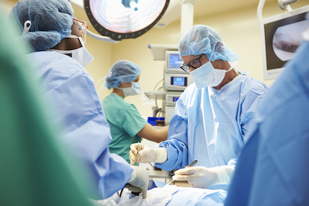 Surgeon and others in blue scrubs operating on a patient